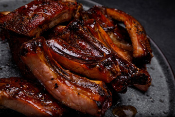 smoked ribs in sauce on a plate on a dark background