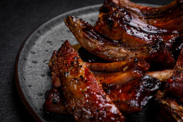 smoked ribs in sauce on a plate on a dark background