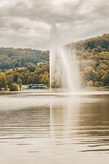 a jet water on lake. autumn landscape. cloudy gray sky. lake with forest
