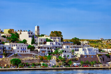 Beautiful summer day, sunshine in typical waterfront of Greek island. Whitewashed houses on hills. Mediterranean vacations. Milos, Cyclades, Greece.