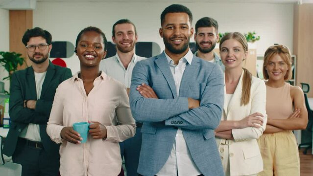 A group of co workers are in a very nice looking office smiling and crossing their arms looking very pleased