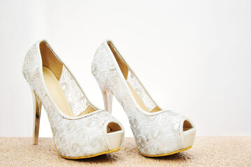 Zapatos de tacón para mujer color plateado con diseño. Calzado formal para fiesta o trabajo sobre un fondo blanco, espacio para texto al lado derecho.
