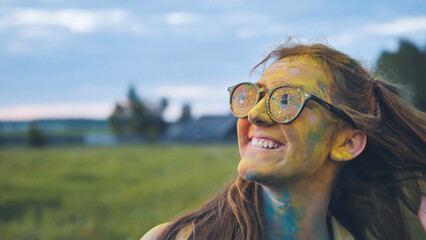 Cheerful girl posing smeared in multi-colored powder.