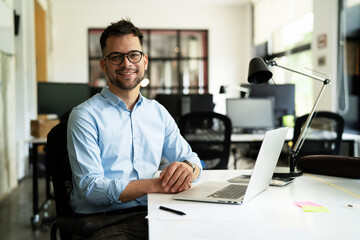 Young businessman using laptop in his office. Handsome man working on the project..