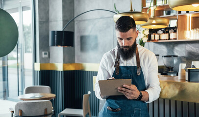 Handsome Barista Doing an Inventory of the Products in a Coffee Shop