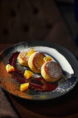 Cheesecakes or cottage cheese pancakes with chocolate sauce and orange on a ceramic plate
