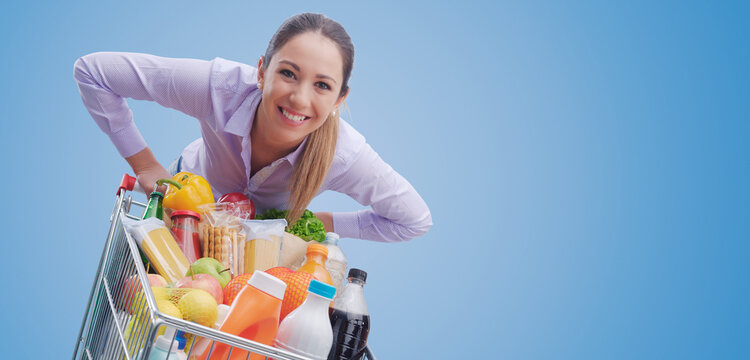 Cheerful woman pushing a full trolley