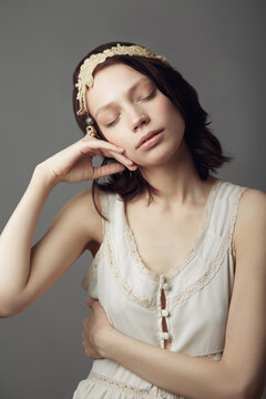 Drifting in a wold of dreams. A beautiful young woman wearing vintage clothing and posing with eyes closed and hand on her cheek.
