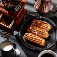 Coffee eclairs on a vintage plate, coffee, coffee grinder.