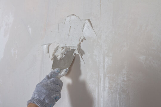 Putty the wall in the house with putty using a spatula to level the surface irregularities