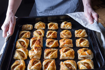 a woman holds a baking sheet with baked homemade cookies with fr