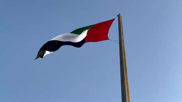 The UAE flag develops in the sky in the wind.