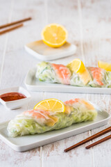 Two summer rolls with salad and prawns on a white wooden background, japanese, asian food, vertical