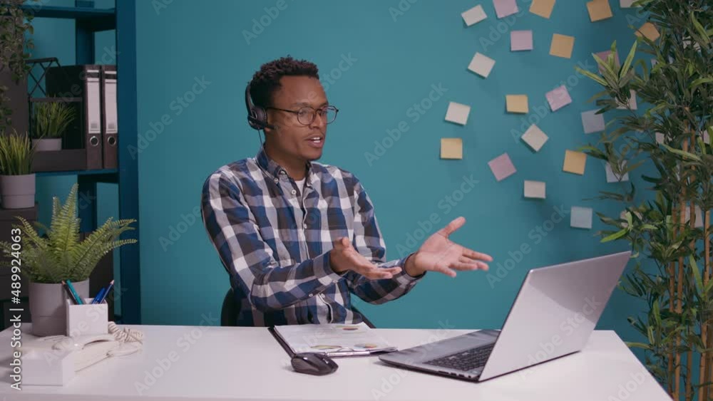 Poster call center operator having argument with client on helpline using headset with microphone and lapto