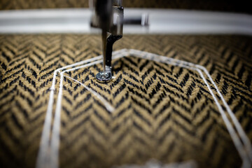 Machine embroidery of ornaments with white thread on cotton brown fabric. Photo with selective...