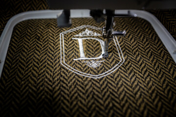 Embroidery design alphabetical monogram D. Machine embroidery with white thread on brown fabrics....