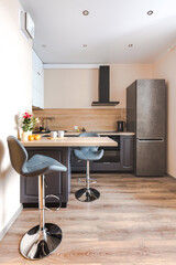 Minimalist wooden grey kitchen with handleless facades and bar table, smart storage system. Kitchen room organization