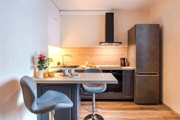 Minimalist wooden grey kitchen with handleless facades and bar table, smart storage system. Kitchen room organization