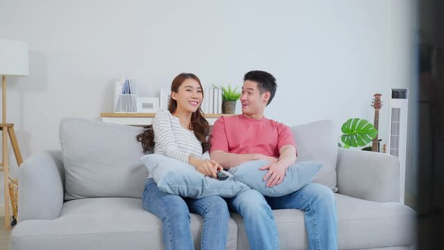 Asian young loving couple watch movie together in living room at home. 