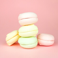 Colorful marshmallows looks like macaroons on pastel pink background, concept of sweet dessert, minimalist trend.