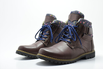 Botas cafés de senderismo para mujer. Calzado para aventura sobre un fondo blanco con espacio para texto a lado izquierdo.