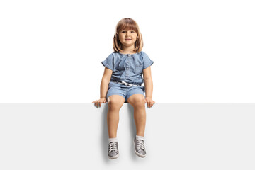 Cute little girl sitting on a blank panel and smiling at camera