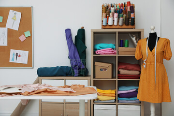 Dressmaking workshop interior with collection of different fabrics and threads