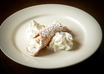 Cannoli on a plate with whipped cream