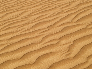 Naklejka na ściany i meble Desert sand. Cropped image of wave-textured desert sand.