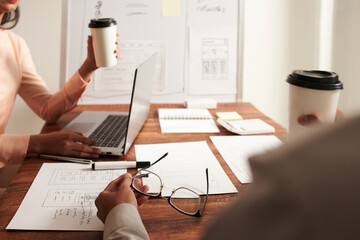 Marketing manager and UI designer discussing mobile application layouts and wireframes at meeting