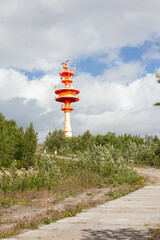 Lighthouse on a mountain slope. With blue sky and clouds. red light tower