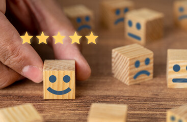 Hand picking smiling faced wooden cube and 5 stars. Symbol of costumer service review and evaluation. Concept consumer satisfaction feedback, survey. 