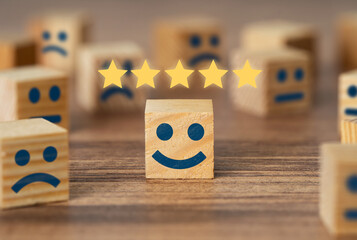Hand picking smiling faced wooden cube and 5 stars. Symbol of costumer service review and...