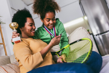 Proud mother feel so excited to see her daughter medal and trophy in her hand after tennis tournament.