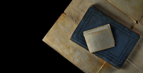 Blank old photo and closed old antique, ancient book isolated on black, top view