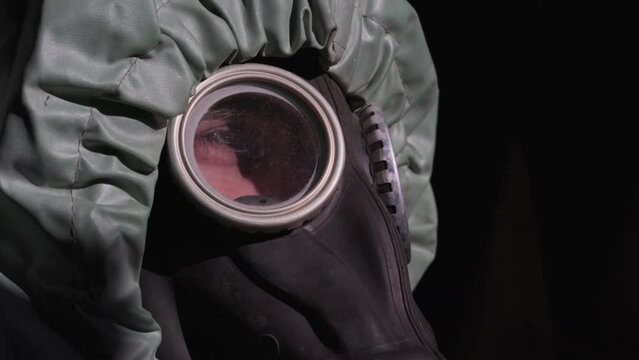 tired person dressed in protection against chemical and bacteriological attack looks thoughtfully on sides through windows of gas mask closeup