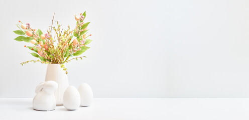 Easter decor in a vase, bunny and eggs on a white table. Easter background with copy space