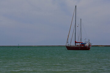 Fototapeta premium Anchored red sailboat-lowered sails-intertidal channels of Ria Formosa. Faro-Portugal-131