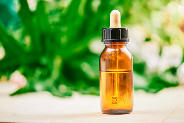 Pipette with CBD cosmetic oil in female hands on a table background with cosmetics, cream with cannabis and hemp leaves, marijuana.