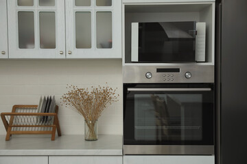 Modern microwave oven on shelf in kitchen