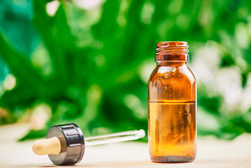 Laboratory CBD oil canister with natural background with hemp plants