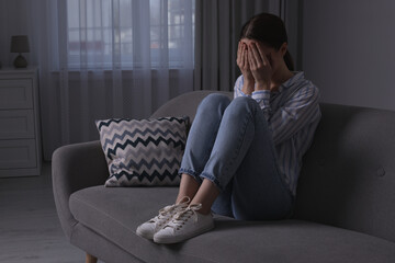 Unhappy young woman crying on sofa at home, space for text. Loneliness concept