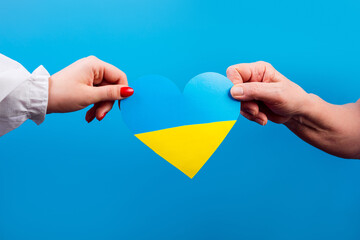 The concept of ending the war in Ukraine. Two hands, an adult and a young one, hold heart of Ukraine. No war. The concept of participation of the Ukrainian people in the war with Russia. Stop Putin