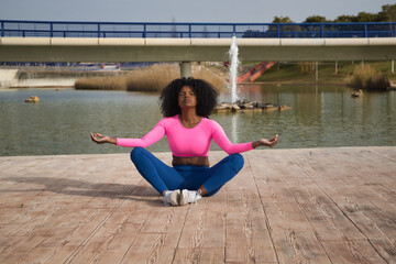 African-American woman with afro hair and sportswear, with fluorescent pink t-shirt and leggings,...