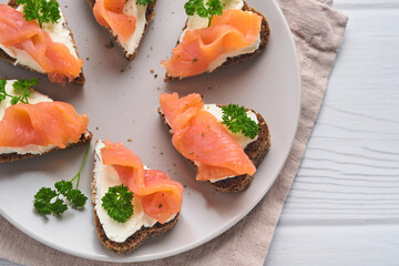 Mini sandwiches with salmon, curd cheese, parsley and rye bread in form of hearts. Valentine's day homemade creative food. Love breakfast design. Selective focus and copy space