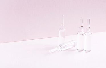 Group of ampoules with liquid on a stylish pink background.