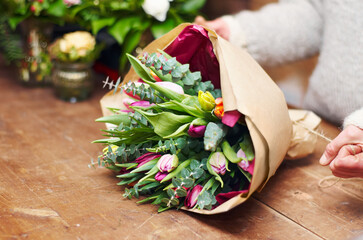 Beautiful bouquet ready for presentation. Cropped shot of a pretty floral bouquet being completed on a wooden counter top.