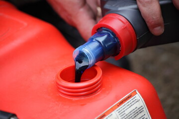 Pouring 2 Т oil into gasoline. Preparation of a fuel mixture for a two stroke outboard motor.
