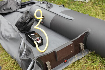 Pumps up an semi-deflated inflatable boat with electric air pump before use - obrazy, fototapety, plakaty