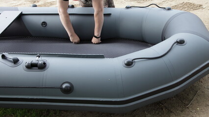 White male hands lay a protective carpet in an inflatable boat with a soft bottom.